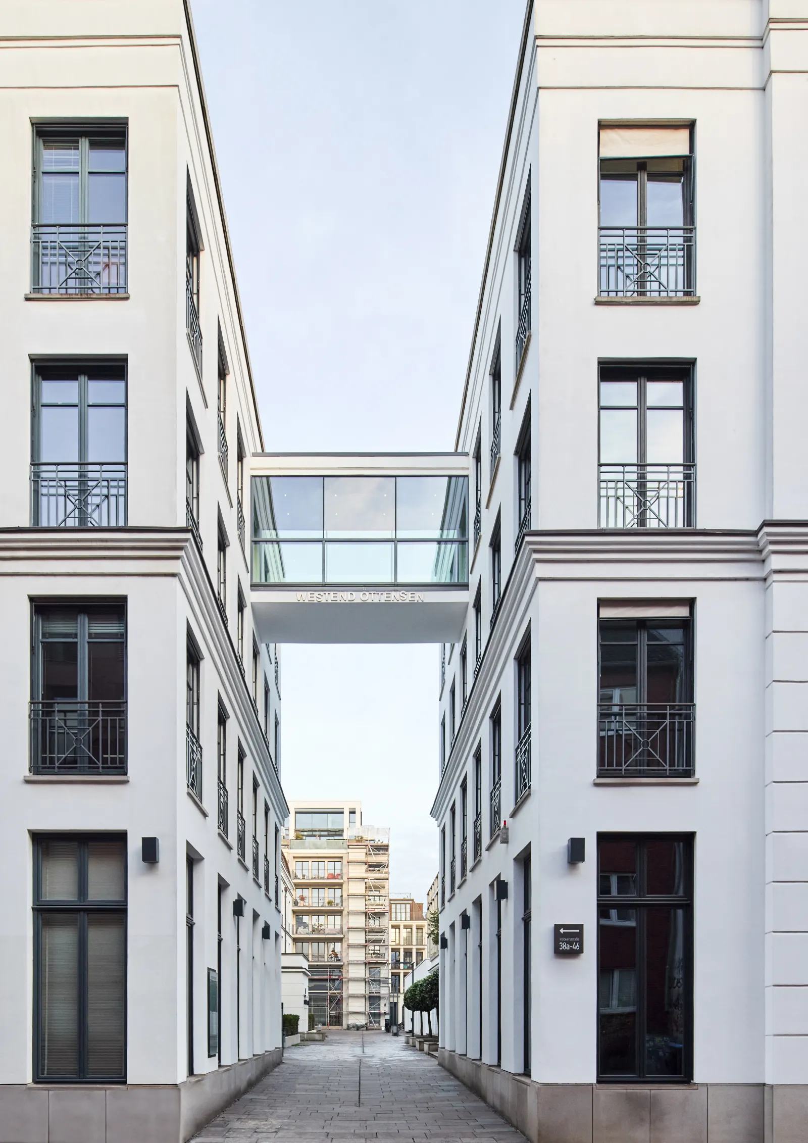 Moderne Bürogebäude mit Glasbrücke verbinden zwei weiße Fassaden in Ottensen, umgeben von einer ruhigen Straße.