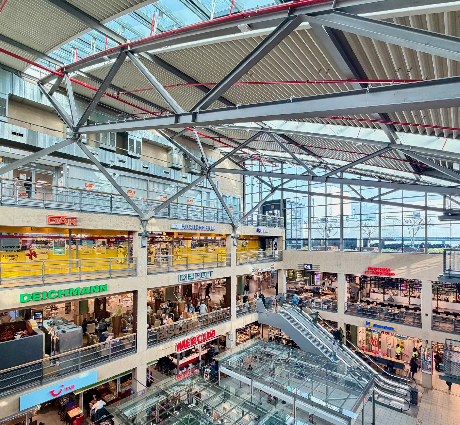 Das Mercado-Einkaufszentrum zeigt mehrere Geschäfte und einen Aufzug, umgeben von modernem architektonischem Design.